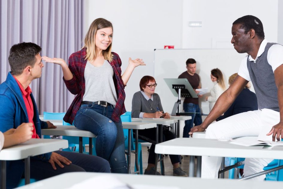 nauczycielka mediująca spór między uczniami przy stole w klasie