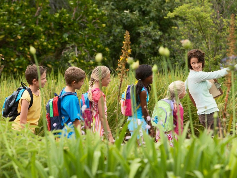 grupa uczniów i nauczycielka przy stole z mapami notatkami i planami wycieczki